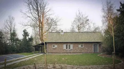 a small brick house in the middle of a yard at De Hoog Weyen in Halen