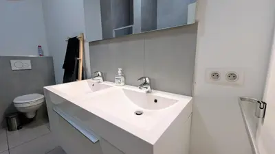 a white bathroom with a sink and a toilet at Augustins in Liège