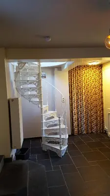 a room with a white spiral staircase next to a window at De Stille Weier in Genk