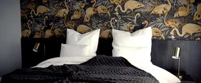 a bedroom with a bed with white pillows and a wallpaper at B&B Sasput in Hasselt