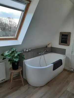 a white bath tub in a bathroom with a window at B&B Eikenlaan 12 in Genk