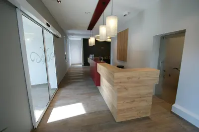 a hallway in a office with a wooden counter and glass doors at Hotel Restaurant Tychon AG in Eynatten