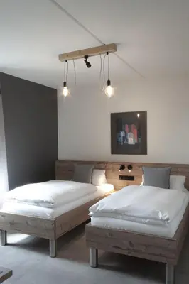 two beds in a room with white walls at Hotel Restaurant Tychon AG in Eynatten