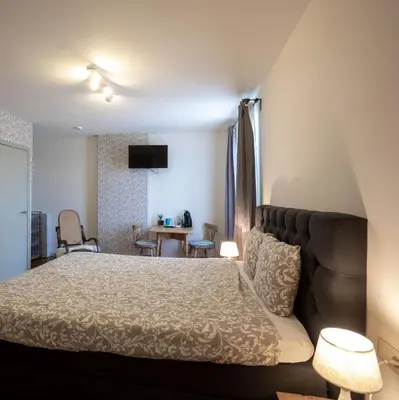 a bedroom with a bed and a couch and a table at B&B De Bloesem in Hoeselt
