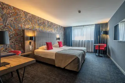 a hotel room with a bed with red pillows at Van der Valk Hotel Liège Congres in Liège