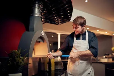 a man standing in a kitchen preparing food at Van der Valk Hotel Liège Congres in Liège