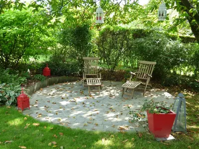 two chairs sitting on a stone patio in a yard at B&B Le Jardin d'Epicure in Olne