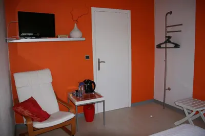 a room with a chair and a table and a tv at B&B Le Jardin d'Epicure in Olne