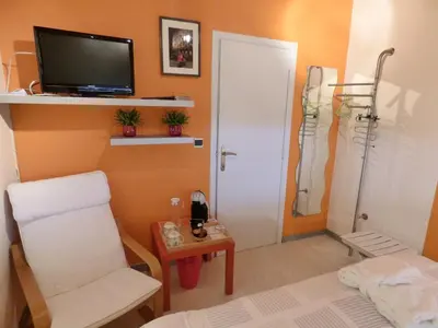 a room with a bed and a chair and a television at B&B Le Jardin d'Epicure in Olne