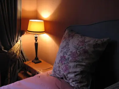 a lamp on a night stand next to a bed with a pillow at De Epicurist in Hasselt