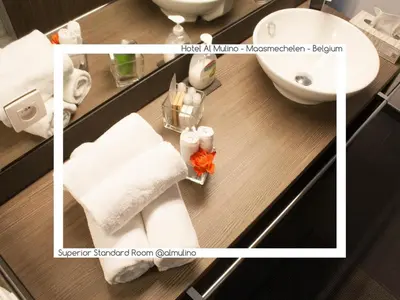 a bathroom with a sink and a toilet and towels at Hotel AL Mulino in Maasmechelen