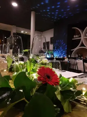 a table with wine glasses and a red flower on it at Hotel AL Mulino in Maasmechelen
