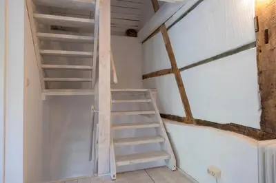 a staircase in a room with white walls and wooden ceilings at Bellevue Maison de Greunebennet in Plombières