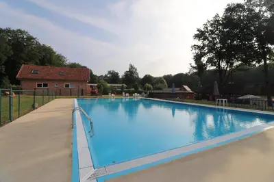 a large blue swimming pool in front of a house at Stefjes Holiday Home in Dilsen-Stokkem