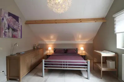 a attic bedroom with a bed and a chandelier at Stefjes Holiday Home in Dilsen-Stokkem
