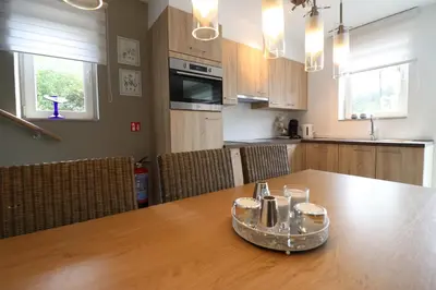 a kitchen with a wooden table with chairs and a dining room at Stefjes Holiday Home in Dilsen-Stokkem