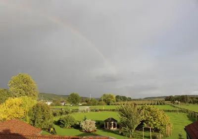 a rainbow in the sky over a green field at B&B Secret Garden Adults only in Voeren