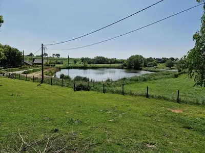 a river in a field with a fence at Gite des étangs à Montzen in Plombières