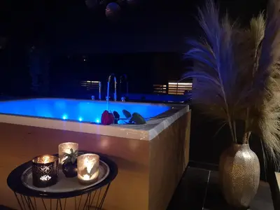 a bathroom with a tub with a table with candles at La bulle D'orée in Chaudfontaine