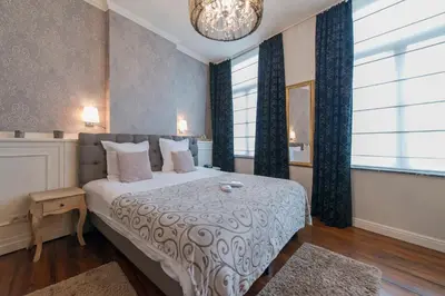 a bedroom with a large bed and two windows at Boutique Hotel Caelus VII in Tongeren