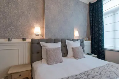 a bedroom with a bed with white sheets and pillows at Boutique Hotel Caelus VII in Tongeren
