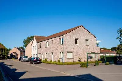 a large brick building with cars parked in a parking lot at Casa Roman - nieuwe vakantiewoning - Deluxe 4p - Relax 4p - Comfort 4p -- ---Cosy 2p in Zonhoven