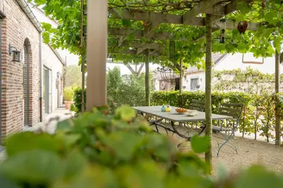 a patio with a table and chairs under a pergola at B&B Woods and Wine in As
