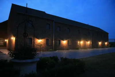 a large brick building with lights on it at night at Hotel Oude Eycke in Maaseik