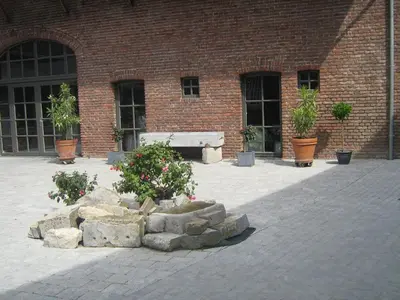 a bench in front of a brick building with potted plants at Hotel Oude Eycke in Maaseik