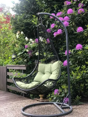 a wicker chair sitting next to a bush with flowers at Holiday Home 'Beautifull Water' in Lanaken