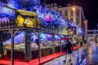 a woman walking down a street in front of a christmas display at Appartement atypique - coeur historique de Liège in Liège