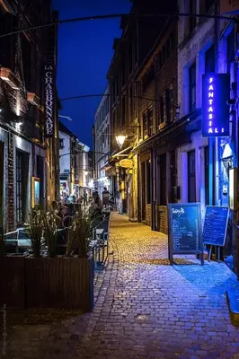 a cobblestone street at night in a city at Appartement atypique - coeur historique de Liège in Liège