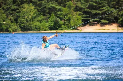 a woman on a surfboard in the water at Hotel De Vossemeren by Center Parcs in Lommel
