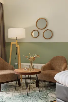 a living room with two chairs and a table and mirrors at Hotel De Vossemeren by Center Parcs in Lommel