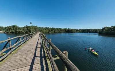a person in a kayak on a river next to a wooden bridge at Hotel De Vossemeren by Center Parcs in Lommel