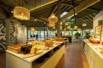 a restaurant with tables and chairs and chandeliers at Hotel De Vossemeren by Center Parcs in Lommel