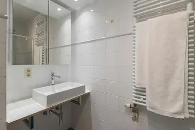 a white bathroom with a sink and a mirror at Studio des princes in Liège