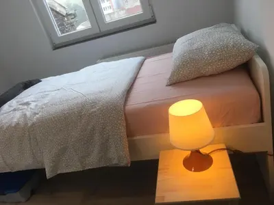 a bedroom with a bed with a yellow lamp on a table at Leonard room in Liège