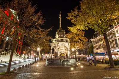 a fountain in the middle of a city at night at Studio des jardins suspendus in Liège