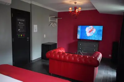 a red living room with a red couch and a tv at L'écrin des Vennes - Liège centre in Liège