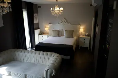 a bedroom with a white bed and a couch at L'écrin des Vennes - Liège centre in Liège