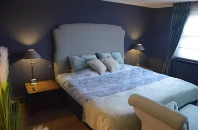 a blue bedroom with a bed with pillows and a chair at B&B Serenity in Pelt