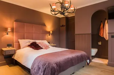 a bedroom with a large bed and a chandelier at B&B Serenity in Pelt