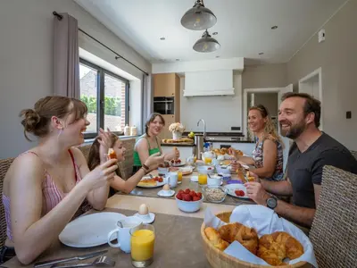 a group of people sitting around a table eating food at Vakantiewoning Mierzicht - privé wellness - Haspengouw 6p in Boekhout