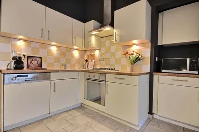 a kitchen with white cabinets and white appliances at Thier à Liege - hauts-sart in Liège