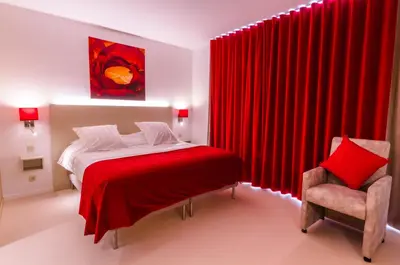 a bedroom with red curtains and a bed and a chair at ManavaHotel in Herstal