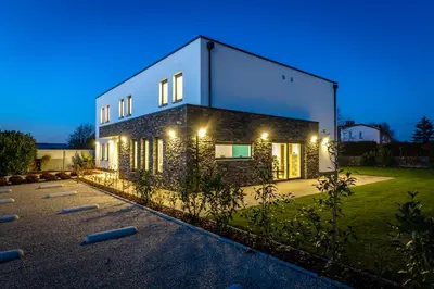a house with a lit up facade at night at ManavaHotel in Herstal