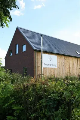 a barn with a sign on the side of it at Wijndomein Zwaeneberg in Voeren