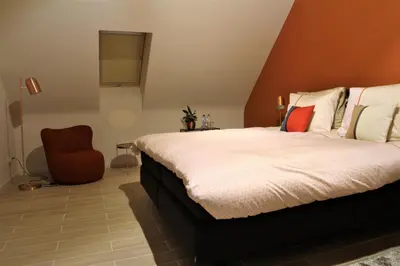 a bedroom with a bed and a chair at Wijndomein Zwaeneberg in Voeren