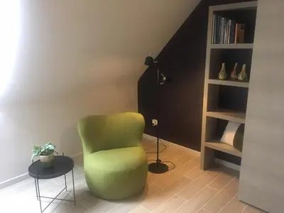 a green chair in a room with a book shelf at Wijndomein Zwaeneberg in Voeren